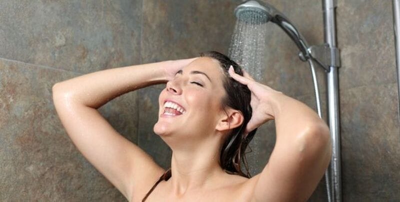 A woman enjoys a hot shower (heat pump hot water)